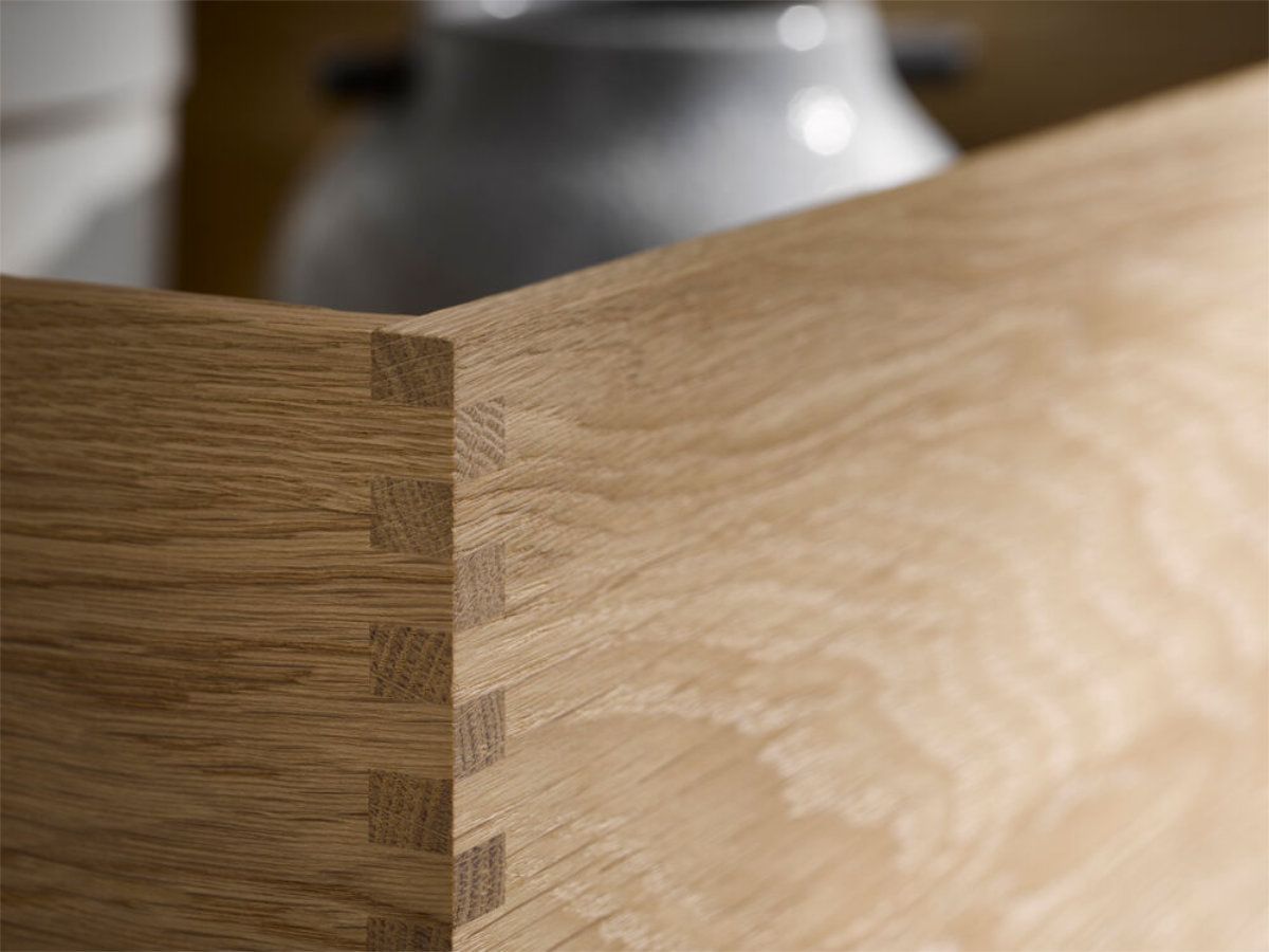 A close up of a wooden box with a vase in the background.