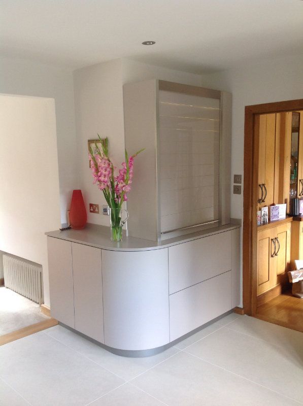 A vase of pink flowers sits on a counter in a kitchen