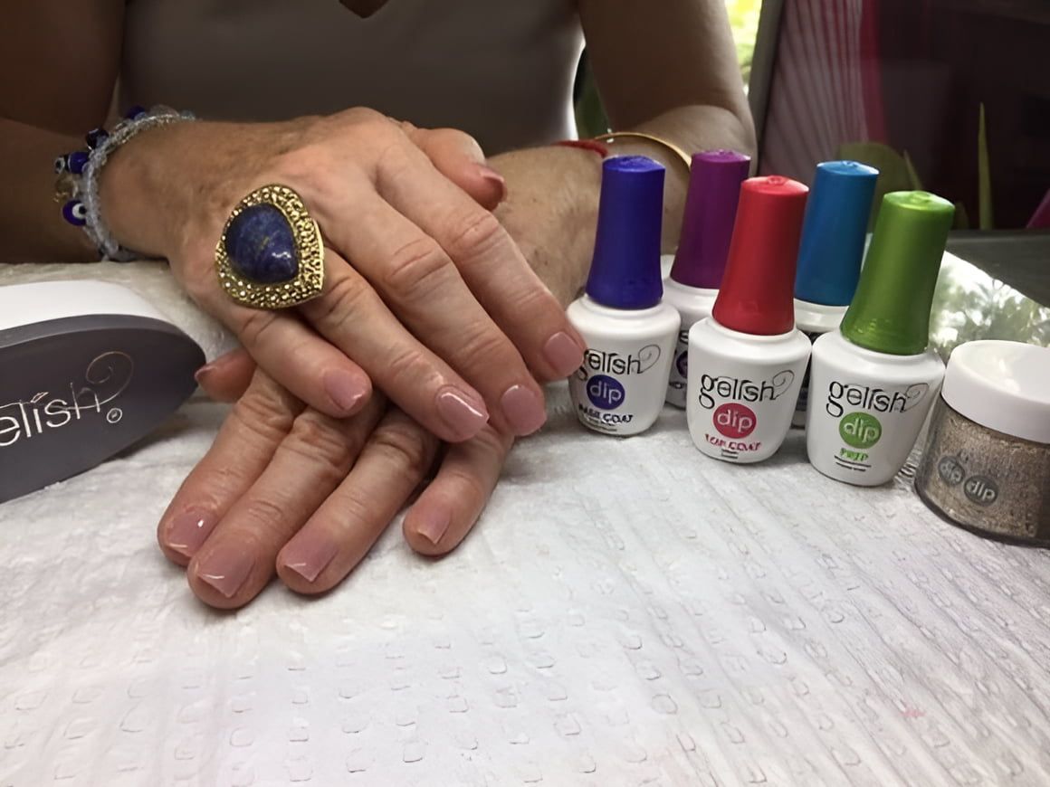 A Woman With a Ring on Her Finger is Sitting at a Table With Bottles of Nail Polish — Nailz By Dezign In Airlie Beach, QLD
