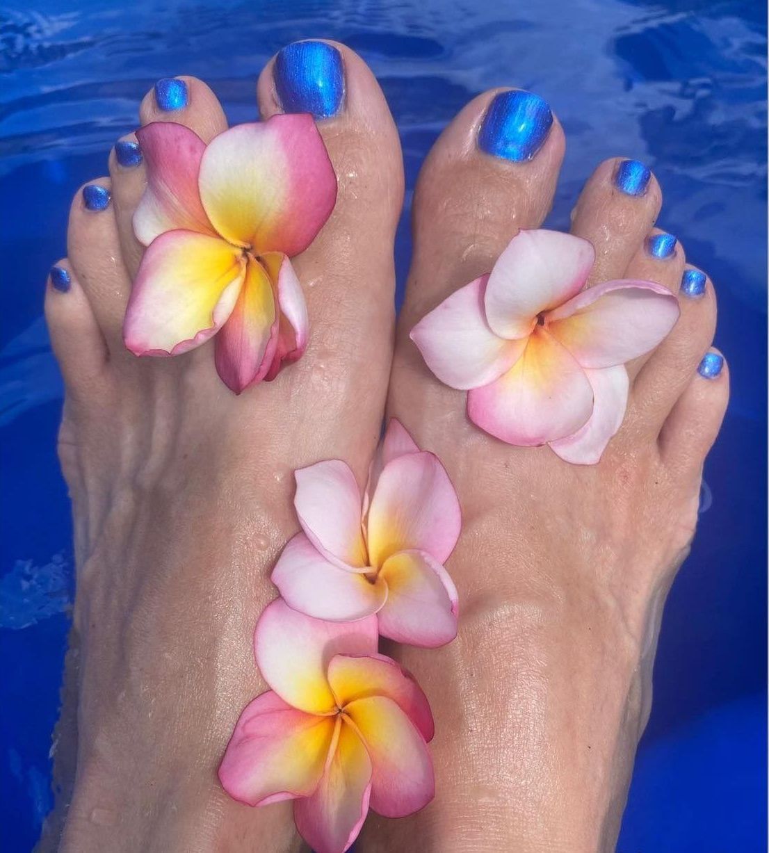 A Woman's Feet With Blue Nail Polish and Pink Flowers — Nailz By Dezign In Airlie Beach, QLD