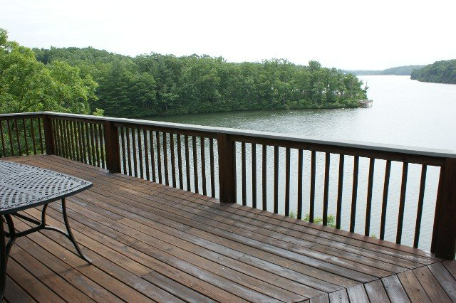A wooden deck with a table and chairs overlooking a lake.