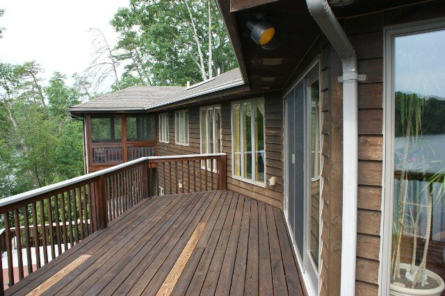 A large wooden deck with a view of a lake