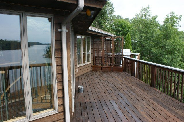 A large wooden deck with a view of a lake