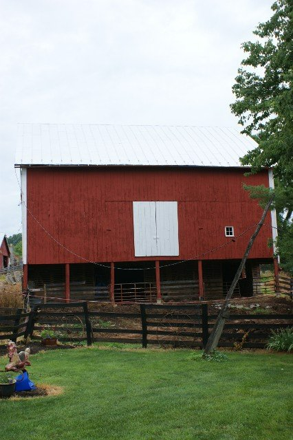 A red barn with a white door is sitting in the middle of a grassy field.