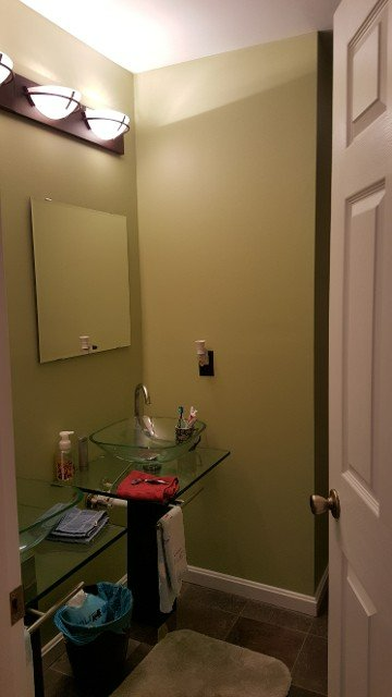 A bathroom with a sink , mirror and trash can