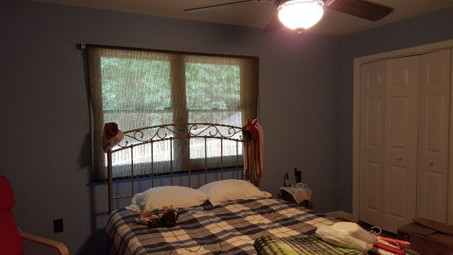 A bedroom with a bed and a ceiling fan