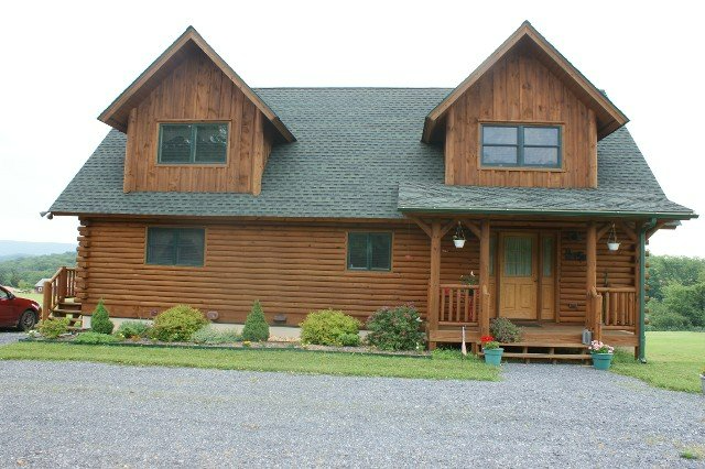 A large log cabin with a car parked in front of it
