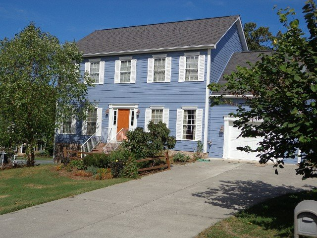 A blue house with white shutters and an orange door