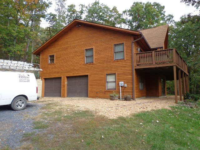 A large log cabin with a white van parked in front of it