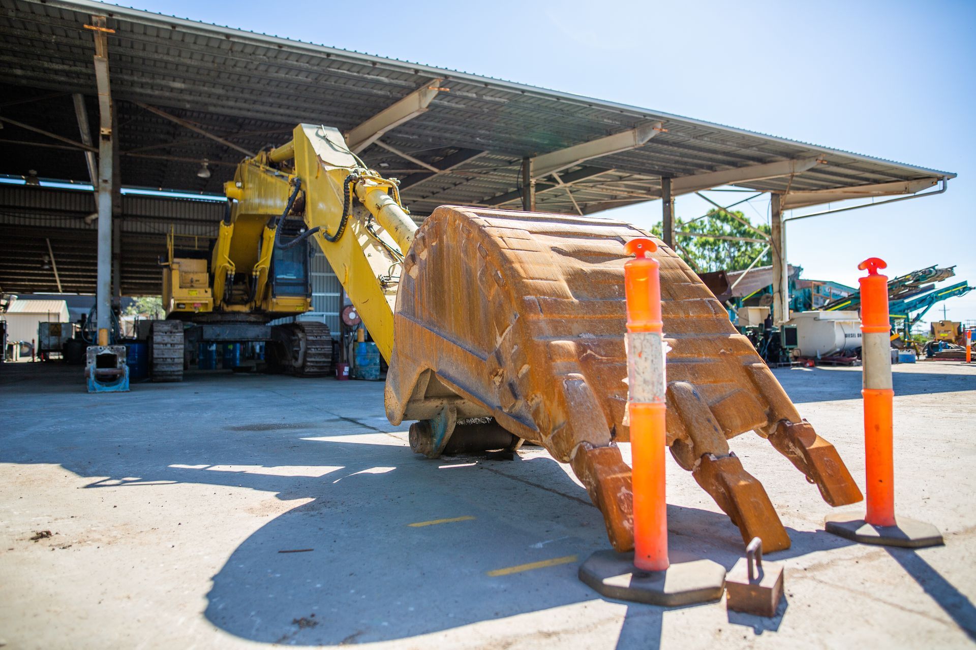A large excavator bucket is sitting on the ground in a parking lot.