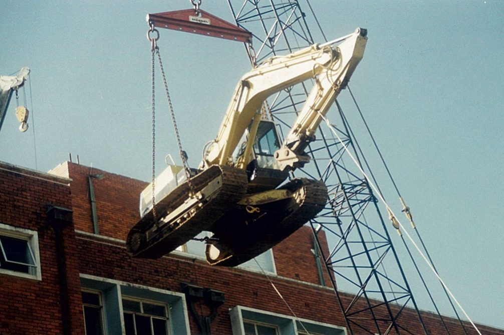 A blue and orange excavator is demolishing a building