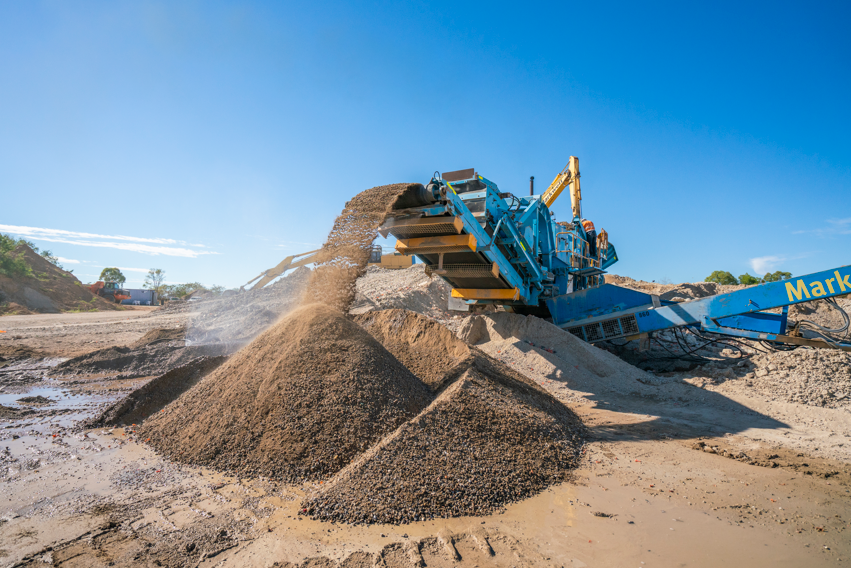 A pile of rocks is being loaded onto a conveyor belt in a quarry.