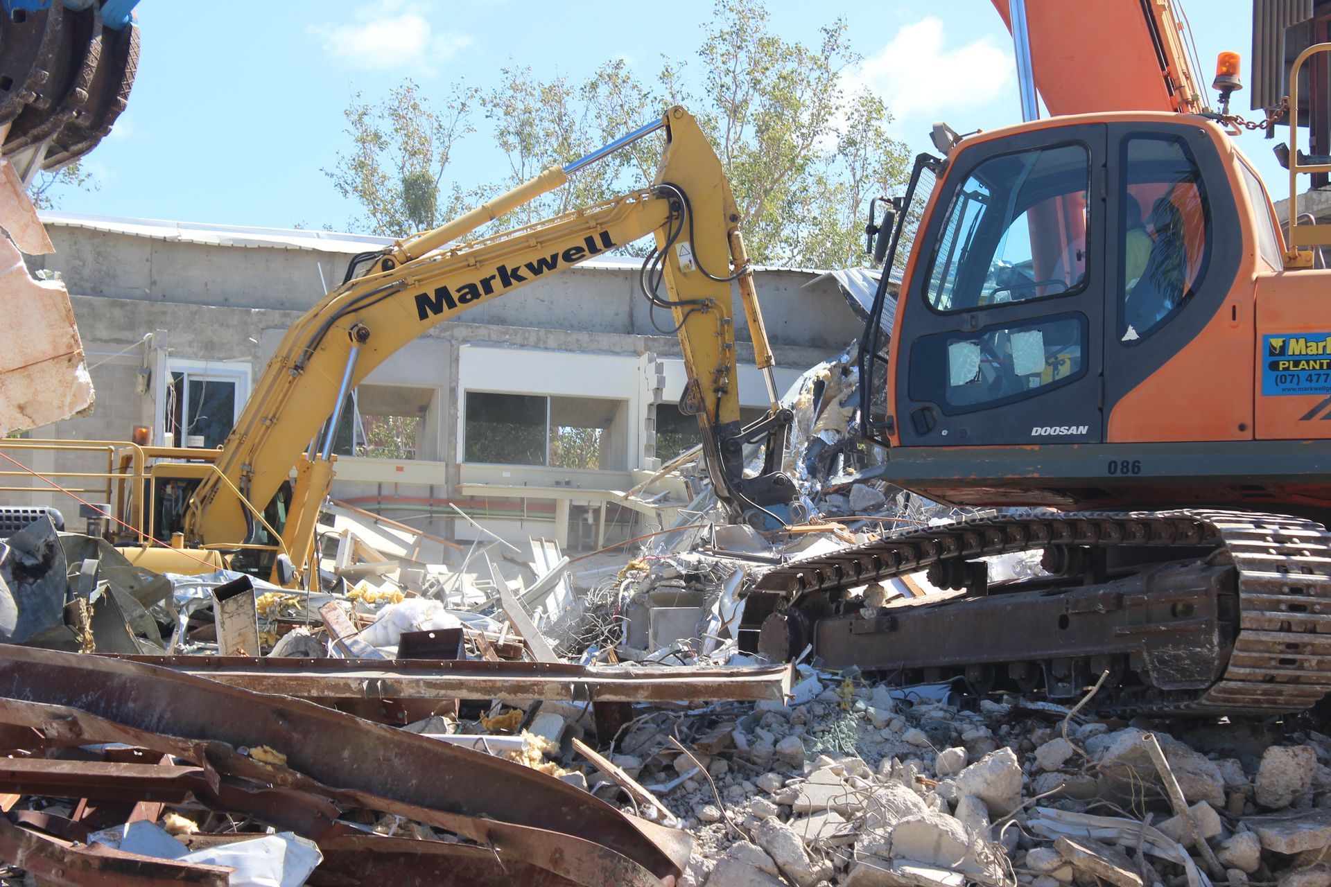 A robotic arm is destroying a building with smoke coming out of it.