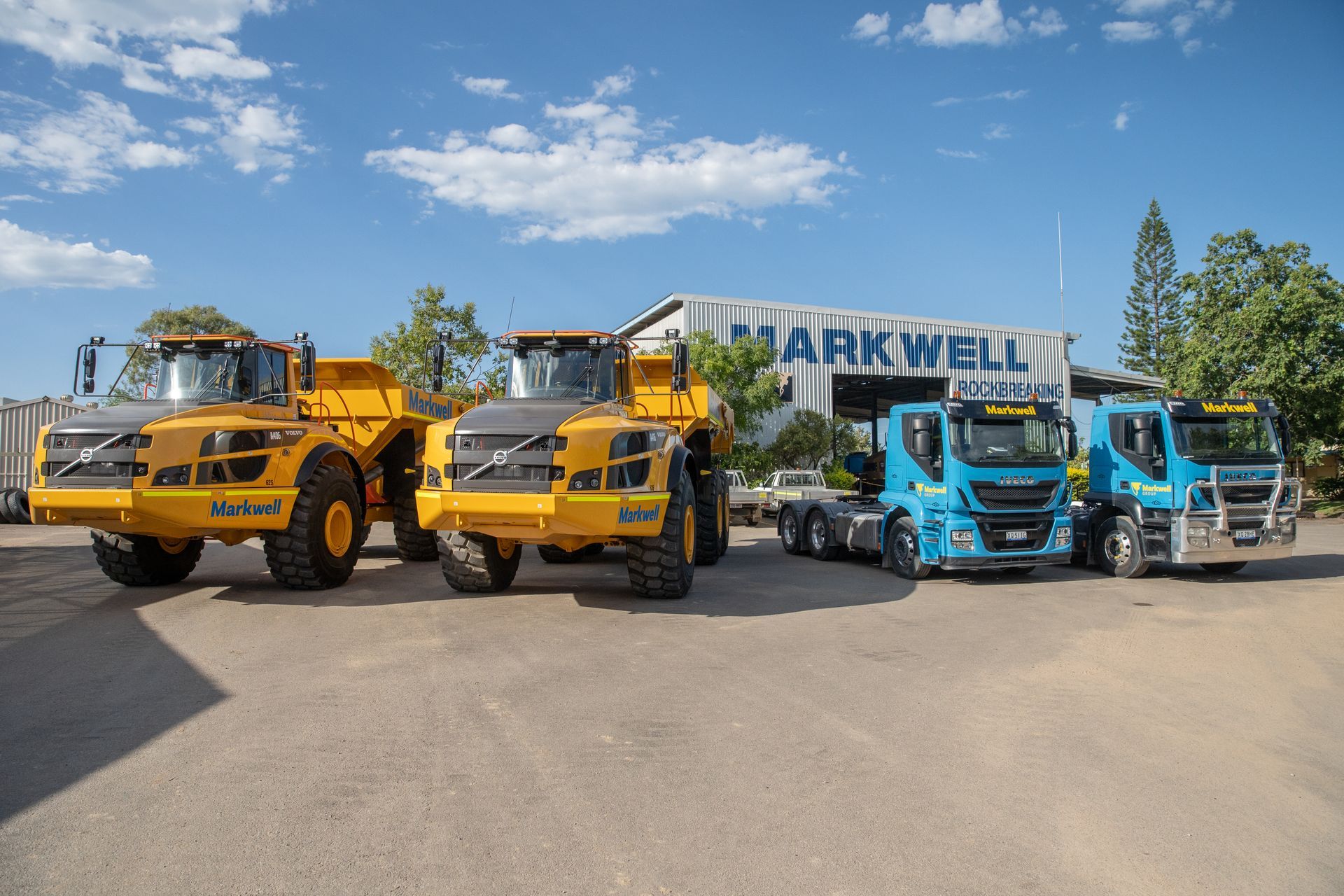 A dump truck is parked under a roof with its hood open.