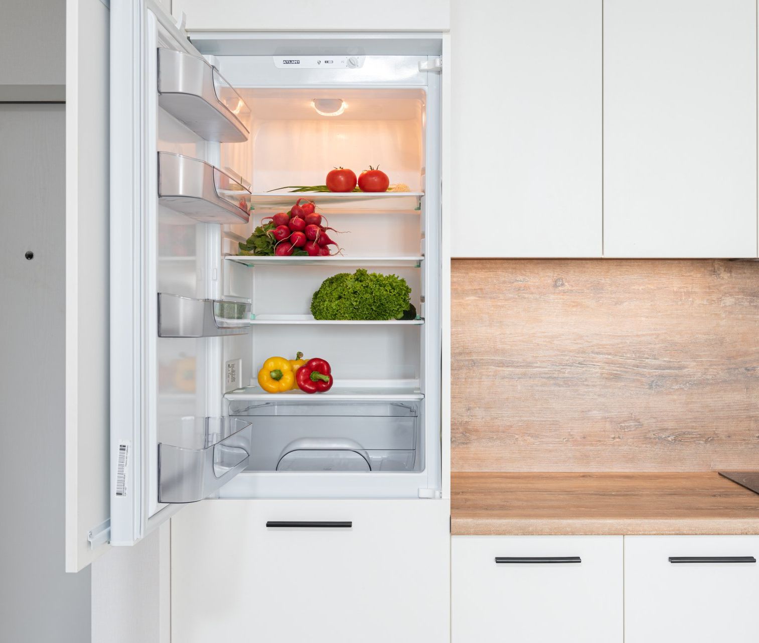 The refrigerator is open and filled with fruits and vegetables.