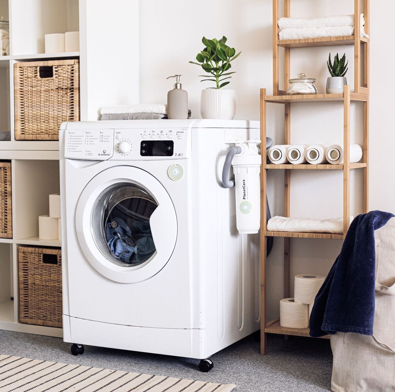 A white washing machine is sitting in a laundry room next to a chair.