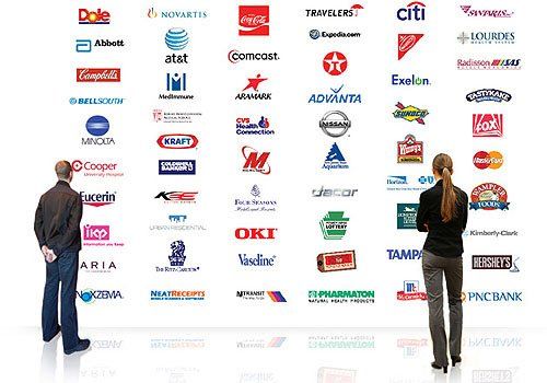 A man and a woman are standing in front of a wall with many logos on it
