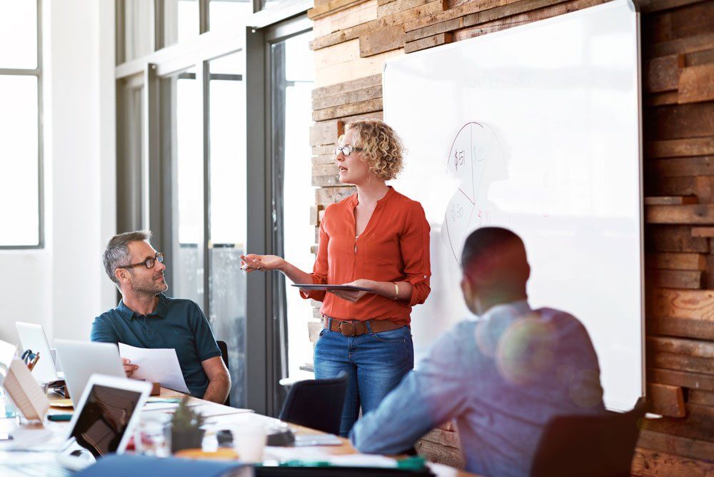 A woman is giving a presentation to a group of people in a conference room.