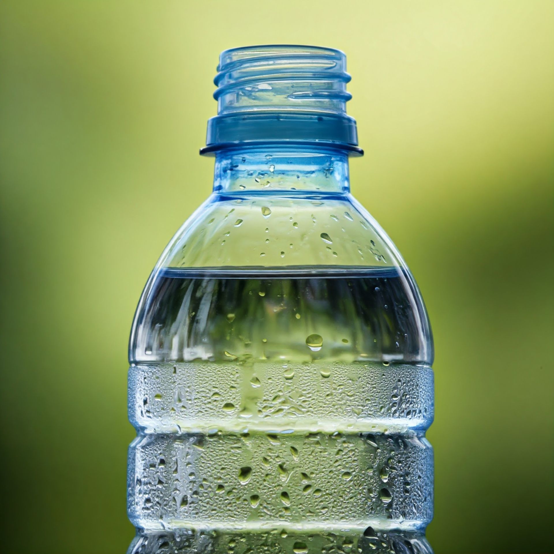 A close up of a bottle of water with water drops on it.