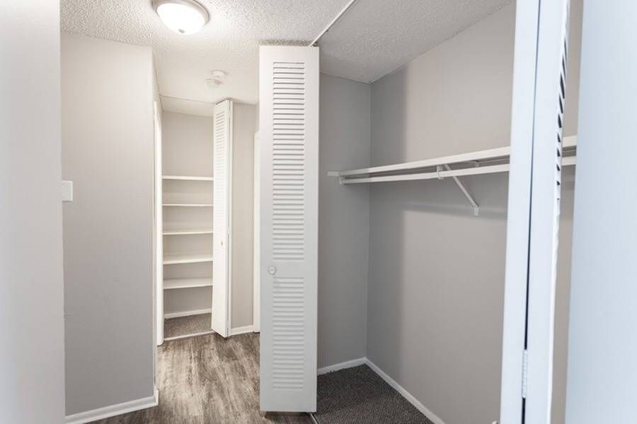 Walk-in closet with white shelves and a hanging rod.