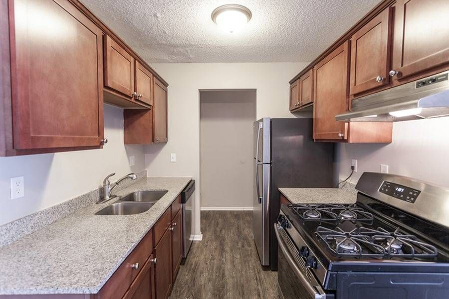 Galley-style kitchen with wooden cabinets, granite countertops, and stainless steel appliances.