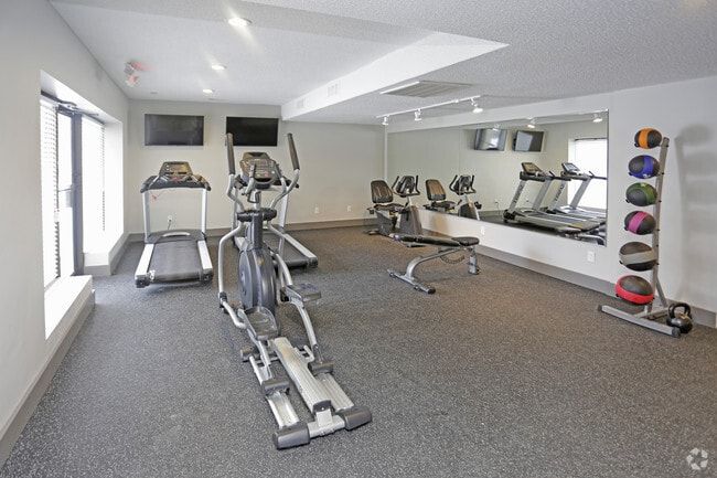 Gym with elliptical machine, treadmill, stationary bikes, weight bench, and exercise balls.