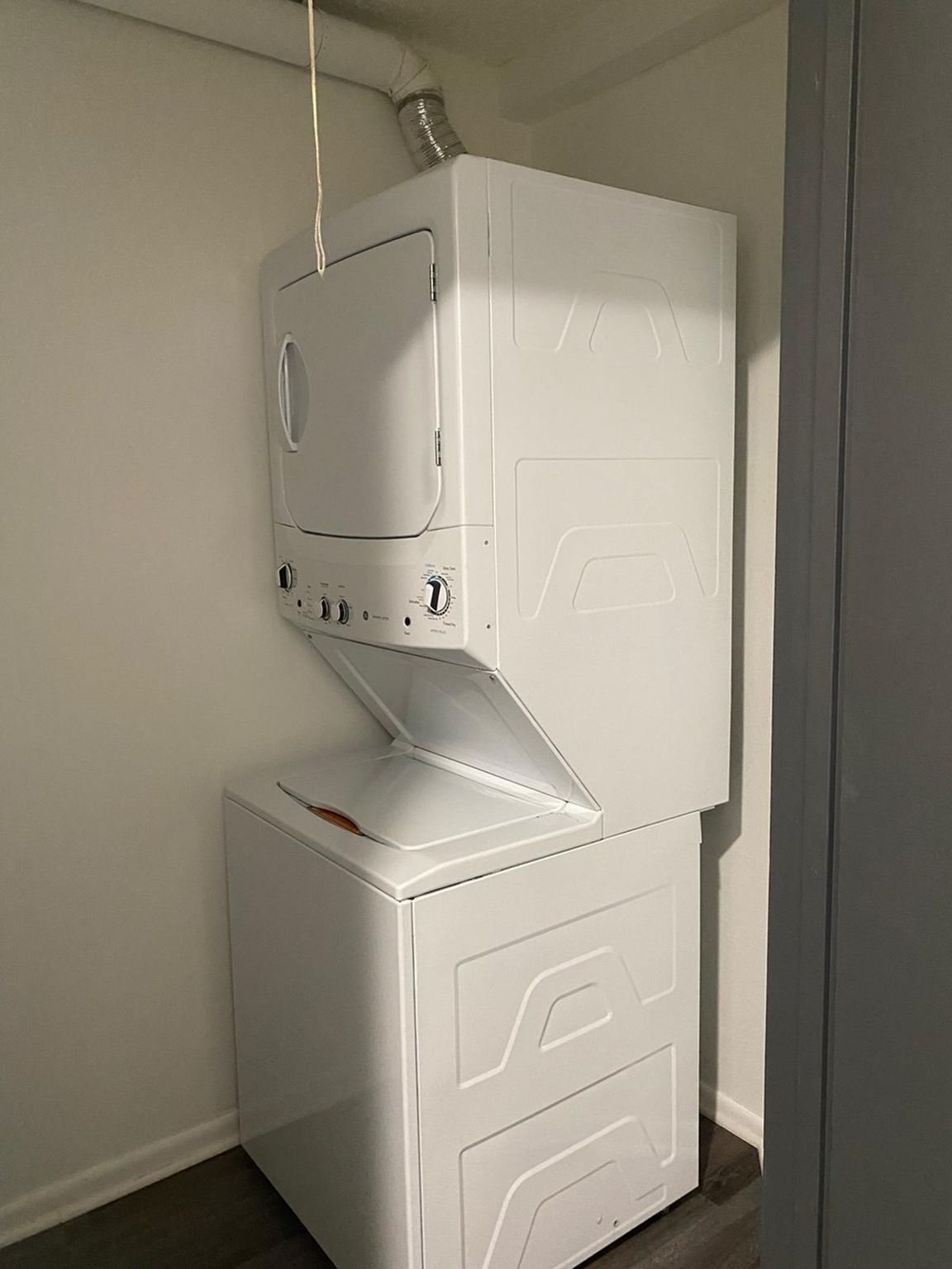 Stacked white washer and dryer in a small laundry closet.