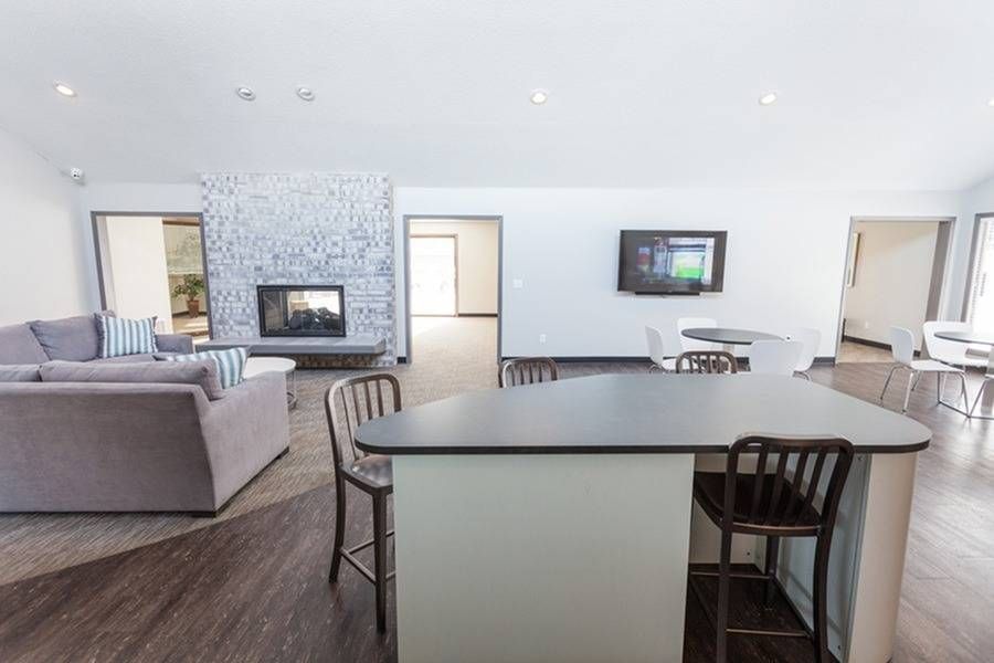 Bright community lounge with a fireplace, TV, sofa, and a large kitchen island.