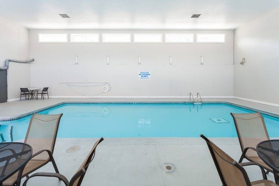 Indoor community pool area with lounge chairs around the pool