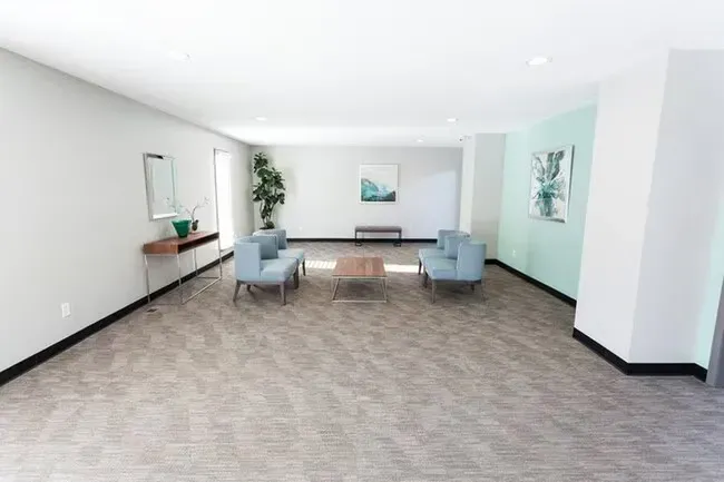 Empty waiting room with blue chairs, artwork, and neutral color scheme.