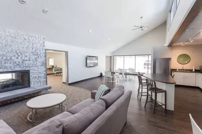 Spacious lounge area with fireplace, sofa, and kitchen bar, with a windowed dining area.