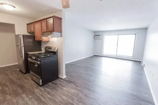 Kitchen and living room with stainless steel appliances, dark cabinets, and gray flooring.