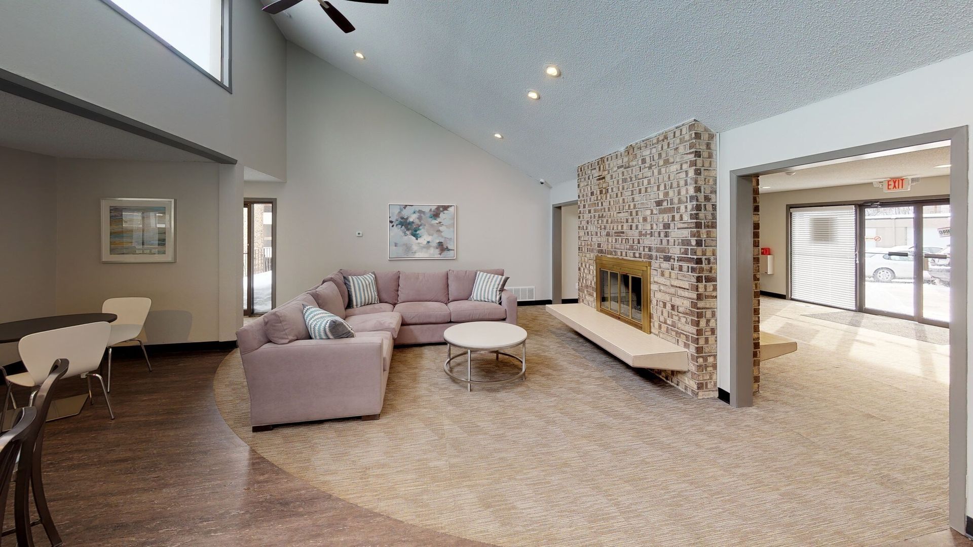 Lounge area with pink sofa, fireplace, and light brown carpet. Entryway and seating area visible.