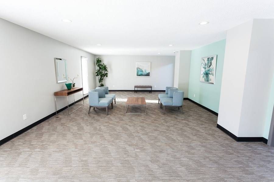 Spacious modern lobby with blue seating, a coffee table, wall art, and a plant.