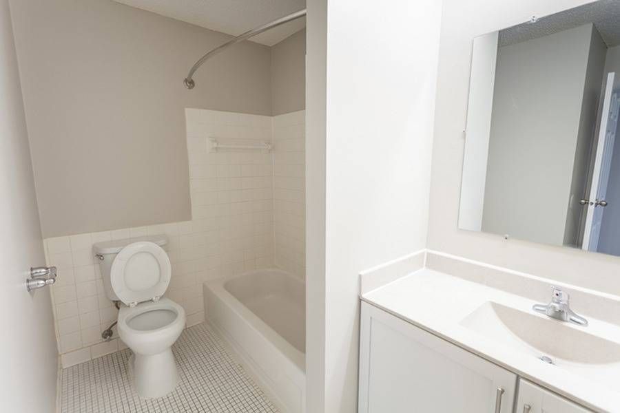 Bathroom in an apartment with a toilet, bathtub, and sink vanity.