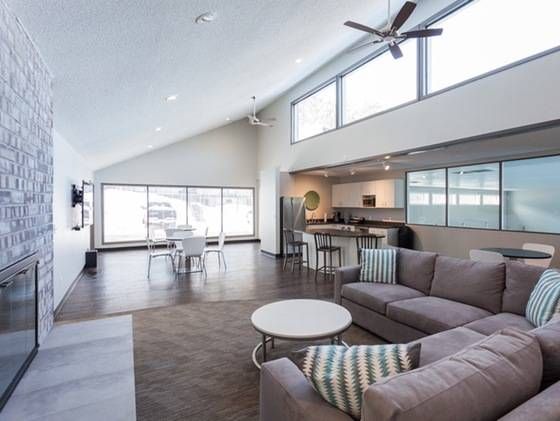 Open-concept living room in a modern apartment with a sofa, coffee table, dining area, and open kitchen.