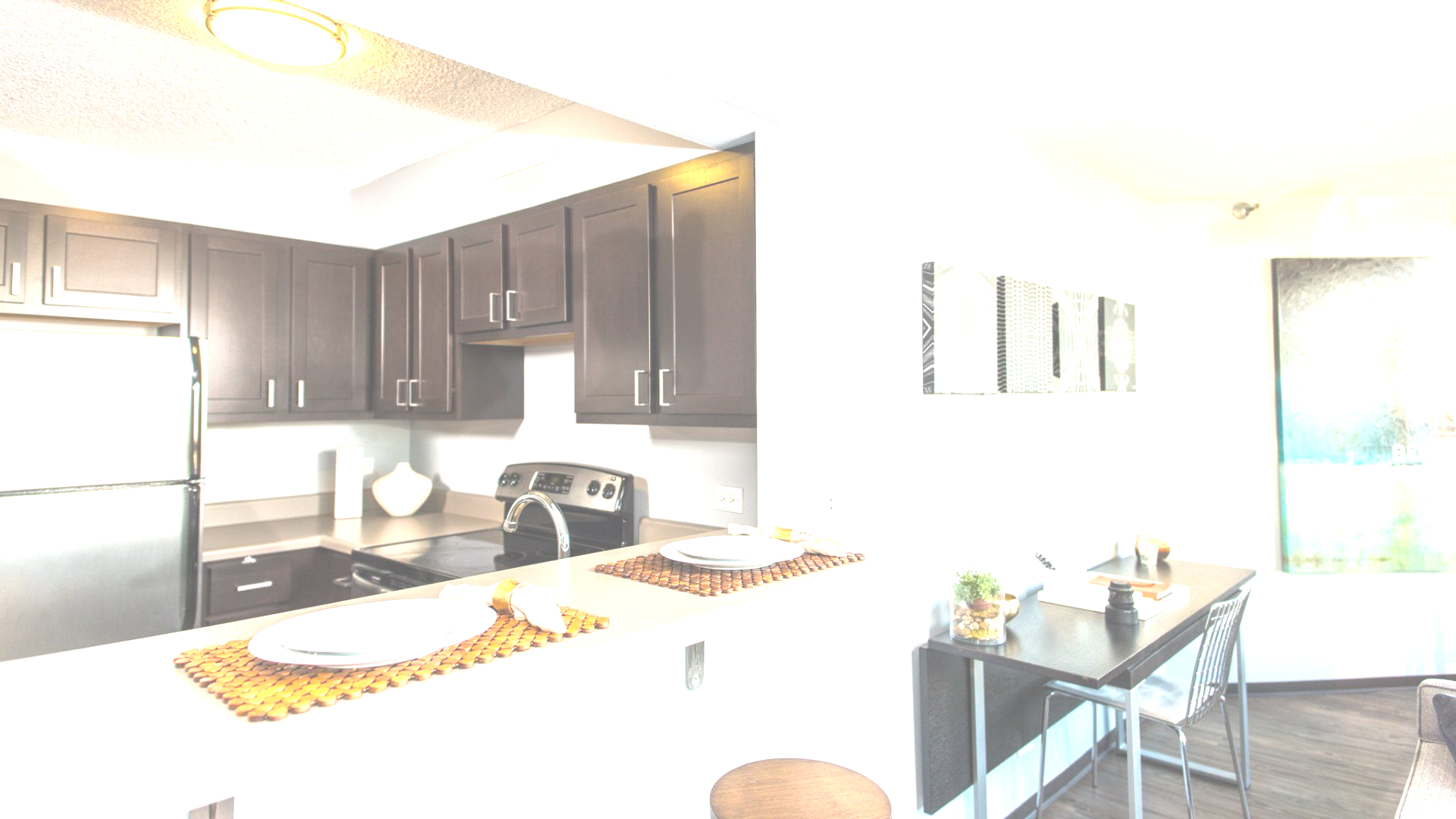 Modern kitchen with dark cabinets, stainless steel appliances, and a breakfast bar.