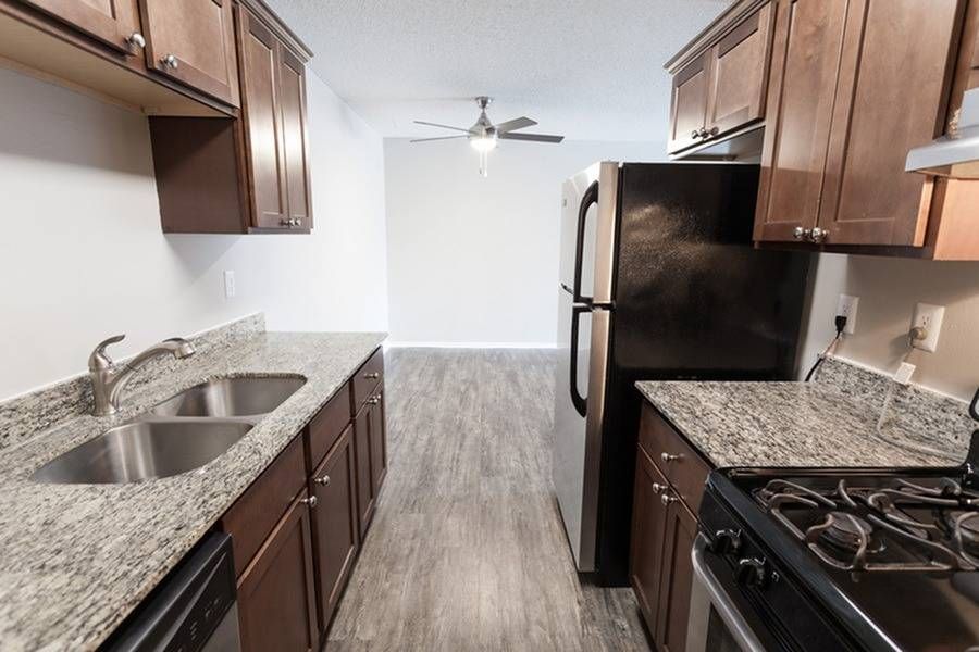 Kitchen with granite countertops, double-basin sink, stainless refrigerator, and stove.