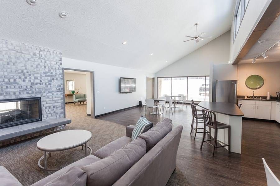 Open community lounge with stone fireplace, comfortable seating, and a kitchenette/bar area.