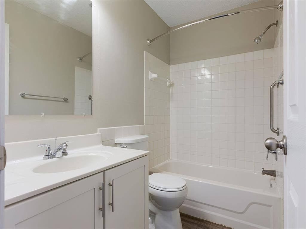 Bathroom in an apartment with a single vanity, sink, toilet, and tiled tub/shower.