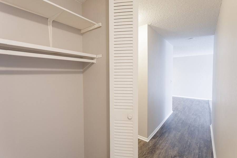 Walk-in closet with a hanging rod and shelves in an apartment hallway.