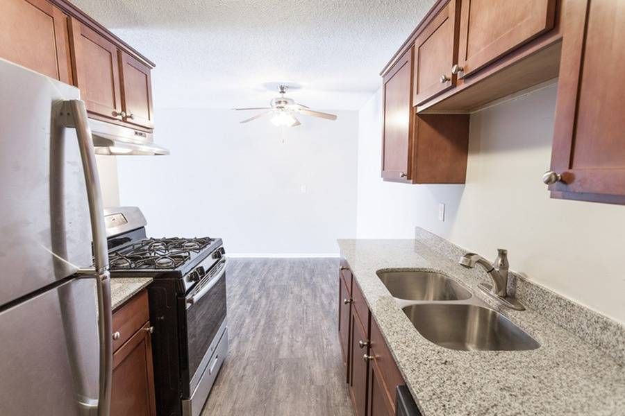 Galley-style apartment kitchen with granite counters, double sink, and stainless steel appliances.