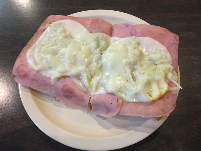 A white plate topped with ham and eggs on a table