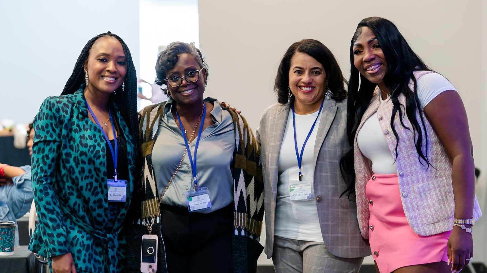 Group of people at an event, smiling and posing.  Some have lanyards. Indoors, bright lighting.