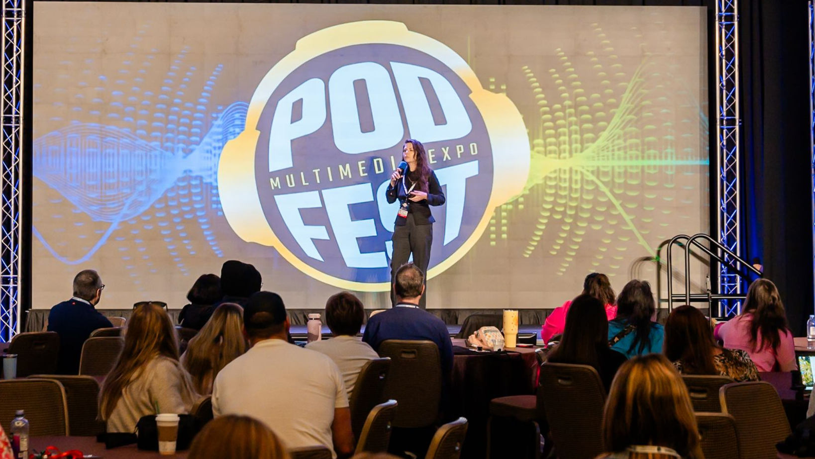 Group of people at an event, smiling and posing.  Some have lanyards. Indoors, bright lighting.