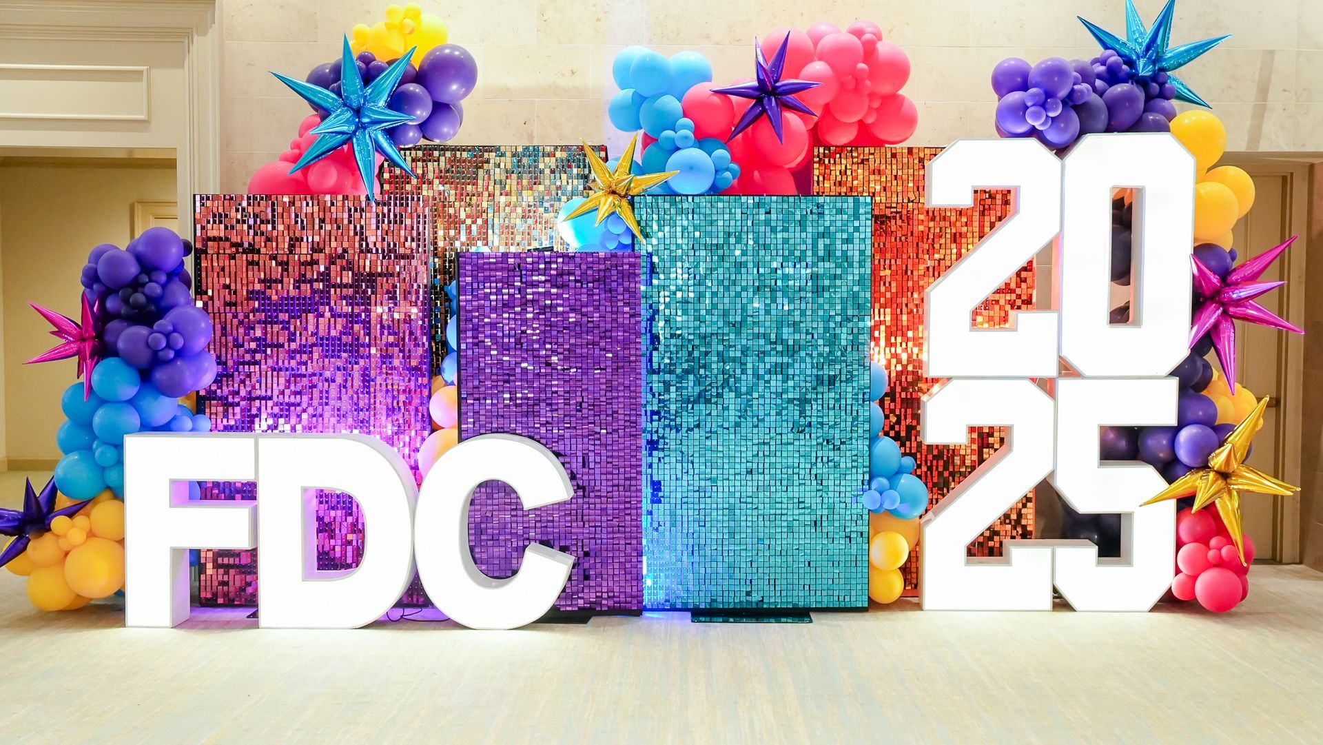 Group of people at an event, smiling and posing.  Some have lanyards. Indoors, bright lighting.