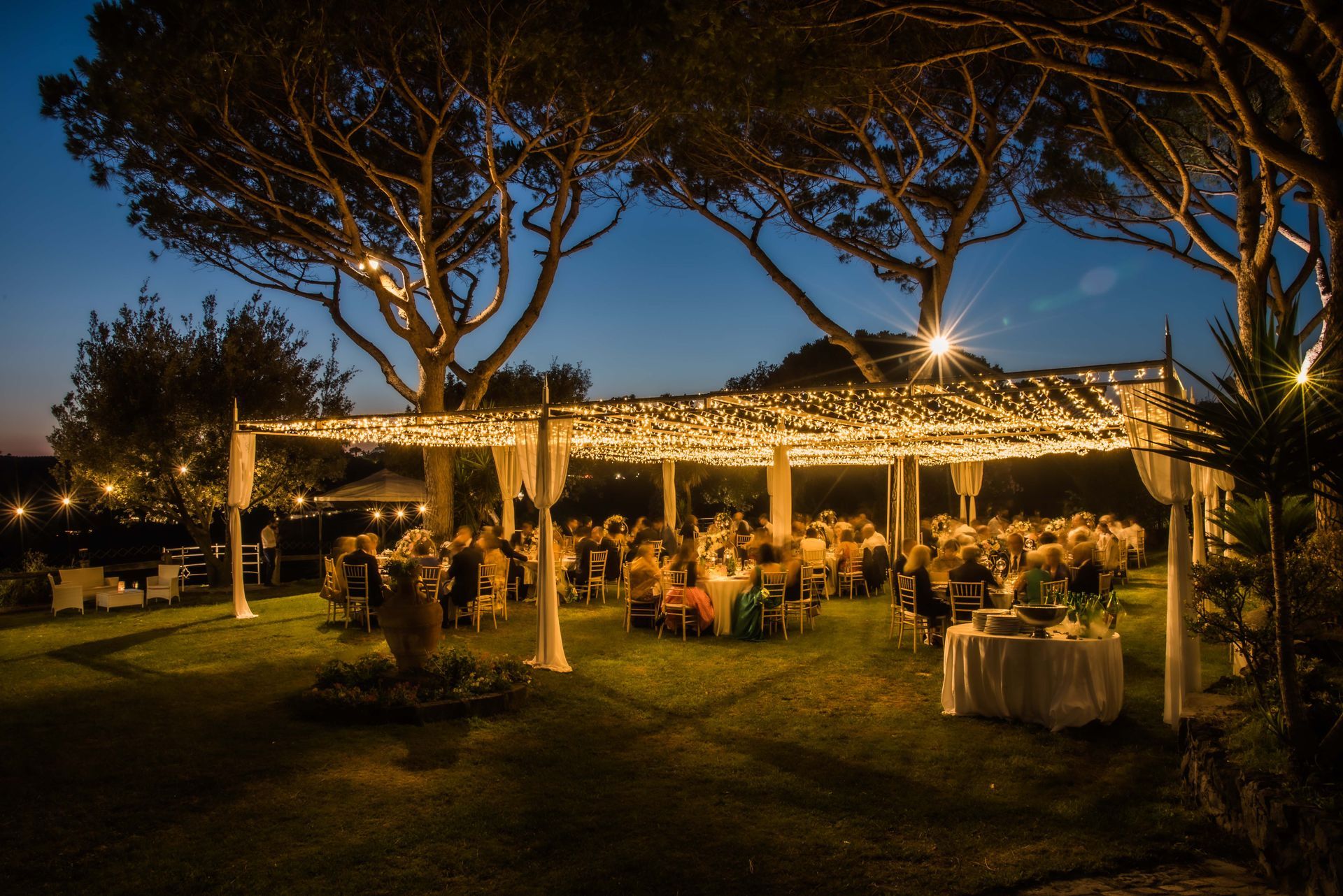 a group of people are sitting under a tent with lights on it