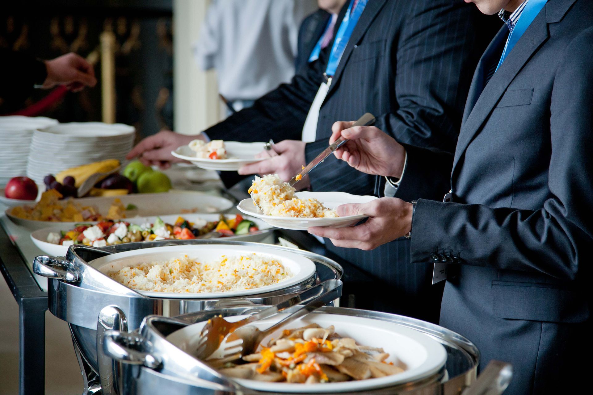 a man in a suit is taking a plate of food from a buffet line