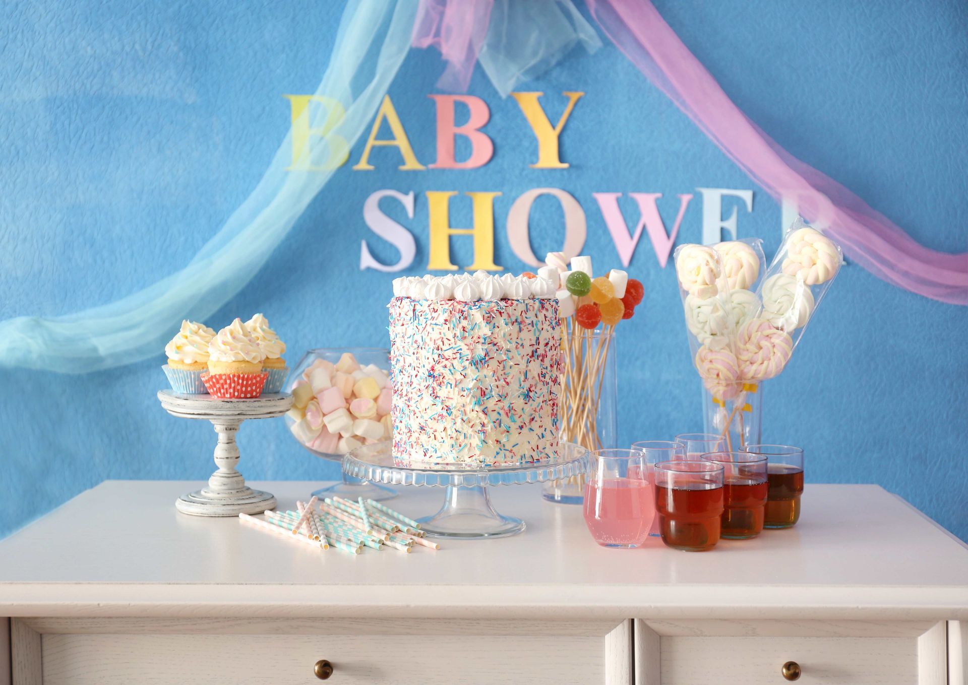 a baby shower table with a cake cupcakes and drinks