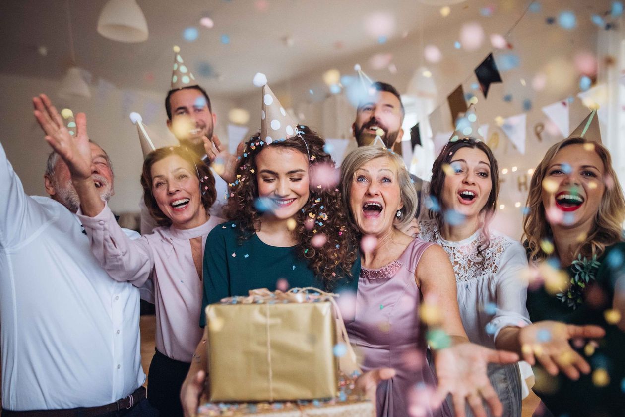 a group of people are celebrating a birthday and throwing confetti in the air